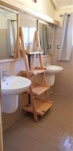 a bathroom with two sinks and a wooden shelf at Diamarek Hotel Sur La Plage in Saint-Louis