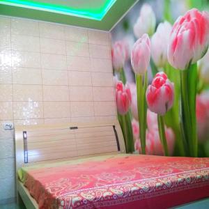 ein Bett mit rosa Tulpen an der Wand in der Unterkunft Апартаменты стадион Металист tulips in Kharkov