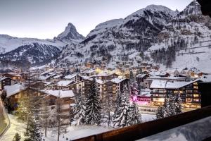 uma cidade coberta de neve com montanhas ao fundo em The Christiania Mountain Spa Resort em Zermatt