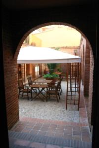 an archway with a table and chairs under a white umbrella at Hostería de la Galería Cerdán in Talavera de la Reina