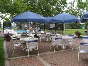 a group of tables and chairs with blue umbrellas at Extended Stay America Suites - Kansas City - Airport - Tiffany Springs in Kansas City