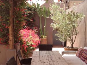 um pátio com uma mesa e algumas plantas e flores em Riad Timila em Marraquexe