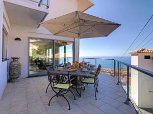 - une table avec des chaises et un parasol sur le balcon dans l'établissement Villa Moniz by LovelyStay, à Funchal