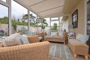 a screened in porch with wicker furniture and windows at The Old Dairy B&B in Exmouth