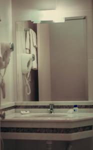 baño con lavabo y espejo grande en Hotel Obino, en São Gabriel