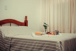 a bed with a table with a vase of flowers on it at Hotel Obino in São Gabriel