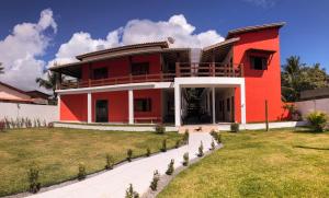 a red house with a lawn in front of it at POUSADA TUPINAMBA in Ilha de Boipeba