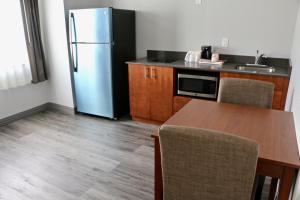 a kitchen with a refrigerator and a table with chairs at Quality Inn & Suites Watertown Fort Drum in Calcium
