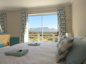 a bed with two towels on it with a large window at Spectrum of views near Muizenberg in Lakeside