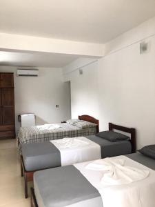 a room with three beds in a room at Pousada Recanto do Teimoso in Ubatuba