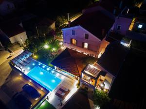 an overhead view of a house with a swimming pool at night at Apartments Guc in Preko
