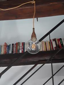 a glass light hanging from a wooden shelf with books at L’Arrocco - La Torre col Mare sul Tetto in Tarquinia