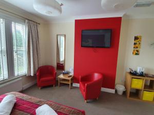 a bedroom with a red wall with a tv and red chairs at The Flowerpot in Derby