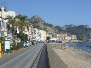 eine Straße in einer Stadt mit Strand und Gebäuden in der Unterkunft CASA NICOLE fronte mare in Giardini-Naxos