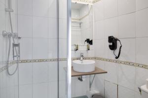 a white bathroom with a sink and a shower at Grand Hôtel Des Gobelins in Paris