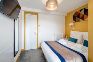 a bedroom with a large bed and a flat screen tv at Grand Hôtel Des Gobelins in Paris