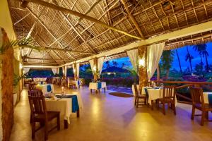 una sala da pranzo con tavoli e sedie in un resort di The Sands Beach Resort a Bwejuu