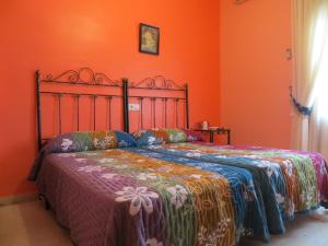 1 dormitorio con 1 cama con pared de color naranja en Hostal Restaurante Reina, en El Tejar