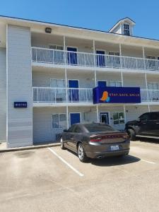 a car parked in a parking lot in front of a building at InTown Suites Extended Stay Houston TX - West Oak in Houston