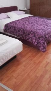 twee bedden met paarse lakens op een houten vloer bij Apartment Gabric in Rab