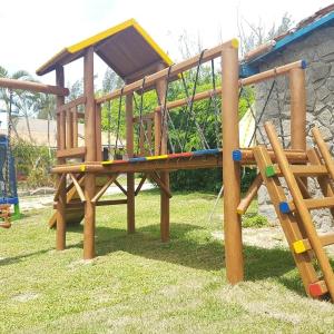a wooden playground with a slide on the grass at Pousada Viva Mar in Saquarema