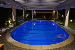 a large blue swimming pool in a backyard at night at Stone Guesthouse in Korinthos