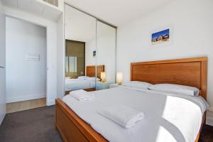 a bedroom with a large bed and a mirror at Swainson at Vue in Adelaide