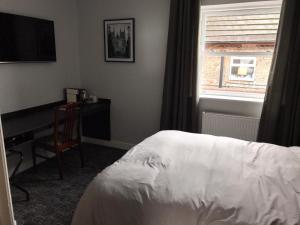 a bedroom with a bed and a desk and a window at Bay horse hotel in Selby