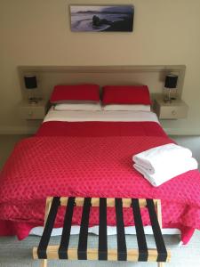 um quarto com uma cama com um edredão vermelho em Pukeko on Bay em Tauranga
