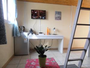 Una habitación con un escritorio, una escalera y una planta. en Petite chambre particulière, en La Force