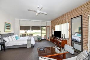 um quarto com uma cama, uma televisão e uma parede de tijolos em Fi's Beach House em Port Macquarie