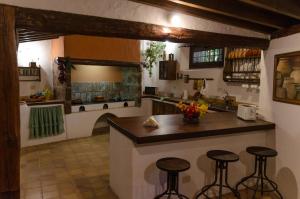 uma cozinha com um balcão e alguns bancos de bar em Rincón de los Abanes - Finca Casa Jardín-VV em San Cristóbal de La Laguna