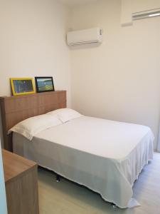 uma cama num quarto com uma cama branca sidx sidx em APTO203-IDP -NA AREIA DA PRAIA em Florianópolis