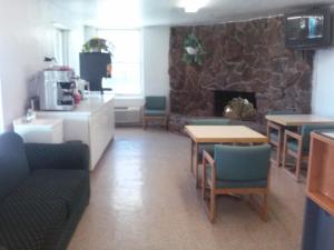 ein Wohnzimmer mit einem Steinkamin sowie Tischen und Stühlen in der Unterkunft Knights Inn Wendover in Wendover