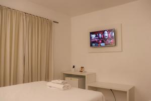 a hotel room with a bed and a tv on the wall at Hotel São Marcos in São Marcos