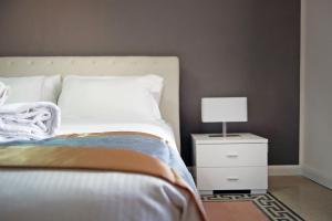 Un dormitorio con una cama y una mesita de noche con una lámpara. en Guardabassi Collection - Vatican White by Varental, en Roma