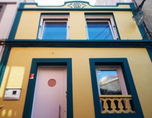 a yellow building with two doors and a balcony at Albergue O Peirao in A Guarda