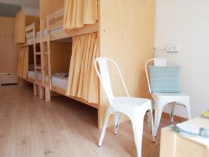 2 Stühle und ein Schreibtisch in einem Zimmer mit Etagenbetten in der Unterkunft Albergue O Peirao in A Guarda