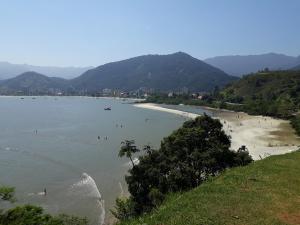 Blick auf einen Strand mit Menschen im Wasser in der Unterkunft CASA NO CENTRO DA CIDADE in Caraguatatuba