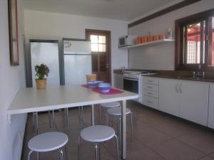 eine Küche mit einem weißen Tisch und 4 Hockern in der Unterkunft Maravilhosa Casa em Angra in Angra dos Reis