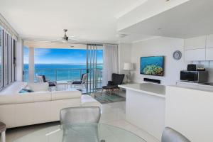 een woonkamer met een witte bank en uitzicht op de oceaan bij Kings Edge Holiday Apartments in Caloundra