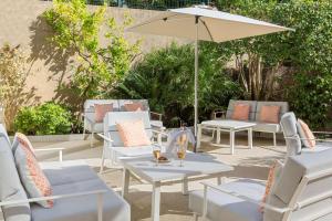 a patio with white tables and chairs and an umbrella at Best Western Hotel Matisse in Sainte-Maxime