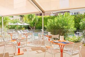 an outdoor patio with tables and chairs and umbrellas at Best Western Hotel Matisse in Sainte-Maxime