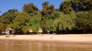 a beach with umbrellas and trees on the shore at La Vilma Hospedaje Familiar in Paganini