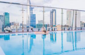 胡志明市的住宿－Happy Life Grand Hotel & Sky Bar，坐在游泳池里俯瞰城市的女人
