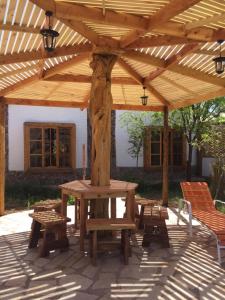 eine hölzerne Pergola mit einem Picknicktisch und Bänken in der Unterkunft Cabaña Media Luna in San Pedro de Atacama