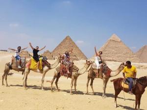 een groep mensen die op kamelen rijden voor piramides bij Queen Pyramids View Inn in Caïro