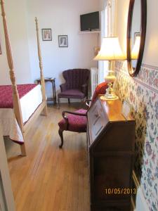 a bedroom with a bed and a lamp and a chair at Louisbourg Harbour Inn in Louisbourg