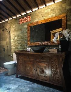 La salle de bains est pourvue d'une coiffeuse avec un lavabo et un miroir. dans l'établissement The Jungle Villa Family, à Ubud