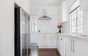 a white kitchen with white cabinets and a refrigerator at Lake Weyba Noosa Lodge & Kangaroos in Peregian Beach